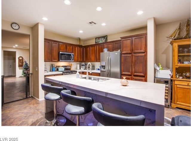 1557 Blue Sierra Ct, Henderson, NV 89074 - kitchen with stainless steel appliances, wine cooler, a center island with sink, recessed lighting, and a kitchen bar