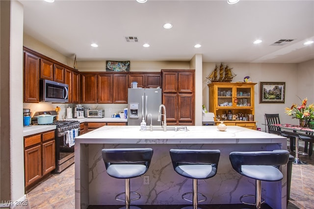 1557 Blue Sierra Ct, Henderson, NV 89074 - kitchen with appliances with stainless steel finishes, a kitchen bar, recessed lighting, an island with sink, and light stone counters