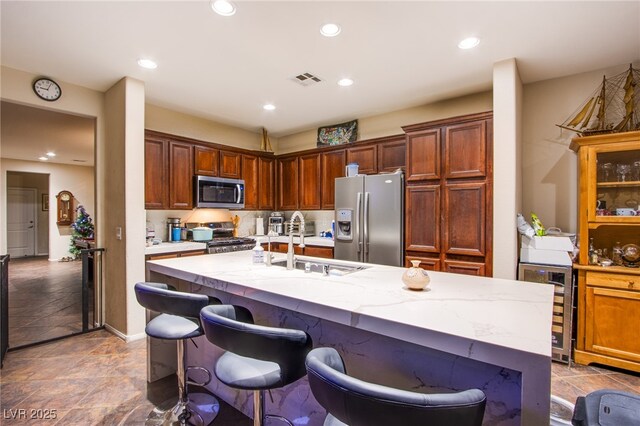 1557 Blue Sierra Ct, Henderson, NV 89074 - kitchen featuring appliances with stainless steel finishes, wine cooler, an island with sink, recessed lighting, and a breakfast bar