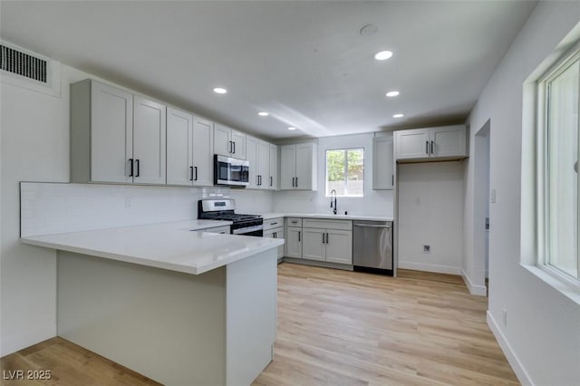 212 View Dr, Las Vegas, NV 89107 - kitchen with appliances with stainless steel finishes, a peninsula, recessed lighting, backsplash, and light wood-style floors