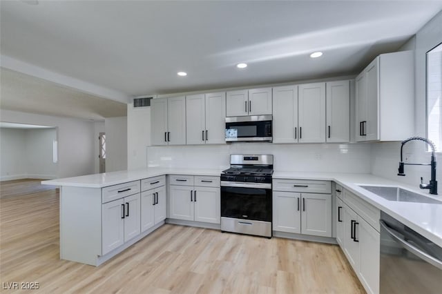 212 View Dr, Las Vegas, NV 89107 - kitchen with stainless steel appliances, a peninsula, light wood-style flooring, backsplash, and recessed lighting