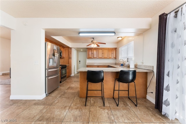 309 Clifton Heights Dr, Las Vegas, NV 89145 - kitchen with stainless steel appliances, a peninsula, light countertops, a ceiling fan, and a breakfast bar