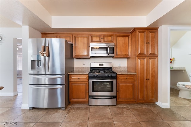 309 Clifton Heights Dr, Las Vegas, NV 89145 - kitchen with stainless steel appliances, brown cabinetry, and light tile patterned floors
