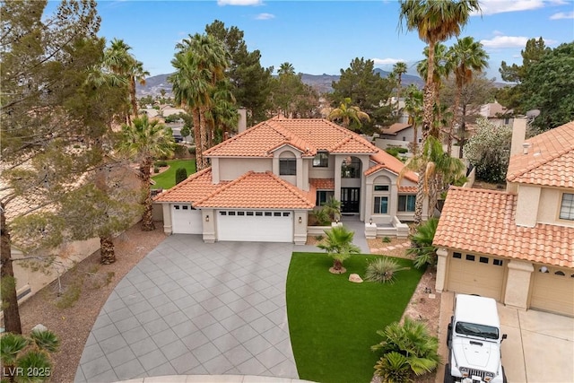 1990 Freeman Ct, Henderson, NV 89014 - mediterranean / spanish-style home featuring a tile roof, stucco siding, a garage, driveway, and a mountain view