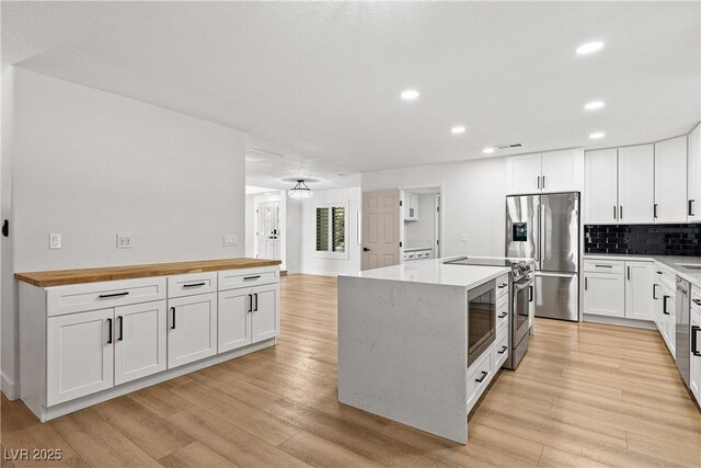 1990 Freeman Ct, Henderson, NV 89014 - kitchen with stainless steel appliances, wood counters, light wood-style flooring, recessed lighting, and white cabinets