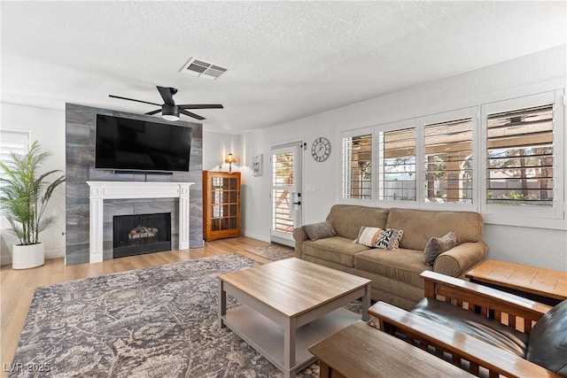 1990 Freeman Ct, Henderson, NV 89014 - living room featuring a ceiling fan, wood finished floors, a tiled fireplace, and a textured ceiling