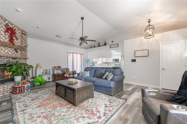2230 Wagon Ave, Pahrump, NV 89048 - living area with light wood-style flooring, lofted ceiling, a ceiling fan, a brick fireplace, and a chandelier