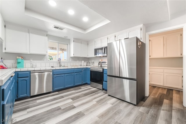 2230 Wagon Ave, Pahrump, NV 89048 - kitchen with appliances with stainless steel finishes, a raised ceiling, blue cabinets, white cabinets, and recessed lighting