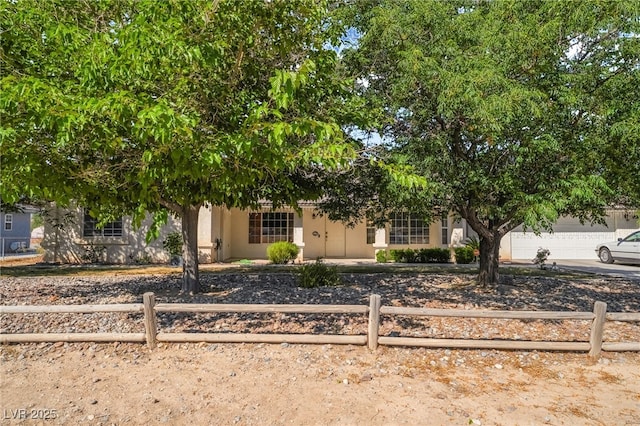 2230 Wagon Ave, Pahrump, NV 89048 - view of property hidden behind natural elements with a fenced front yard, stucco siding, concrete driveway, and an attached garage