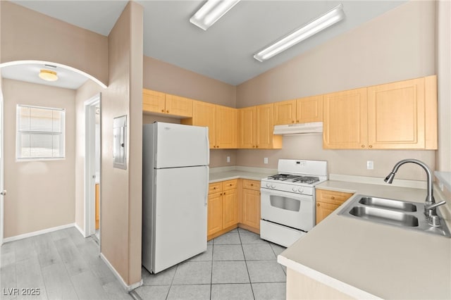 9338 Square Dance Pl Unit 101, Las Vegas, NV 89178 - kitchen with white appliances, under cabinet range hood, light brown cabinetry, arched walkways, and light countertops