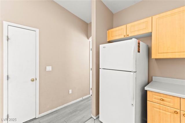 9338 Square Dance Pl Unit 101, Las Vegas, NV 89178 - kitchen with freestanding refrigerator, light brown cabinetry, light wood-type flooring, and light countertops