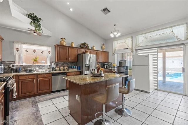 6292 Belgium Dr, Las Vegas, NV 89122 - kitchen with appliances with stainless steel finishes, tasteful backsplash, a center island, light stone counters, and light tile patterned floors