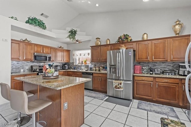 6292 Belgium Dr, Las Vegas, NV 89122 - kitchen with appliances with stainless steel finishes, high vaulted ceiling, tasteful backsplash, and brown cabinetry
