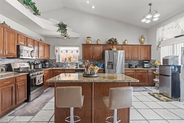 6292 Belgium Dr, Las Vegas, NV 89122 - kitchen with appliances with stainless steel finishes, light tile patterned floors, a center island, tasteful backsplash, and light stone counters
