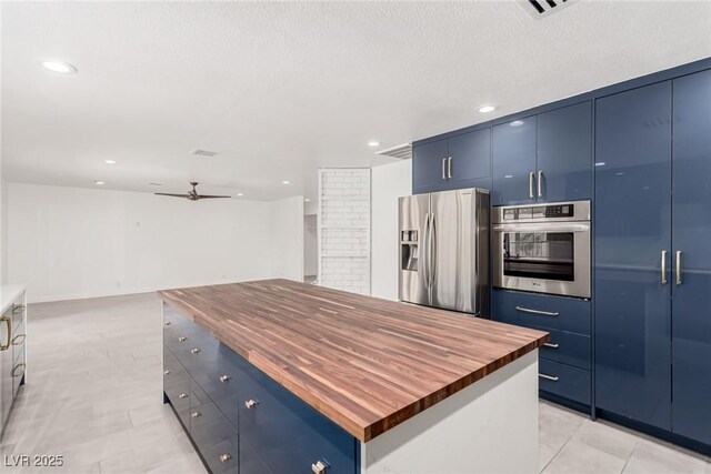 9660 W Ann Rd, Las Vegas, NV 89149 - kitchen with wood counters, stainless steel appliances, blue cabinetry, ceiling fan, and recessed lighting