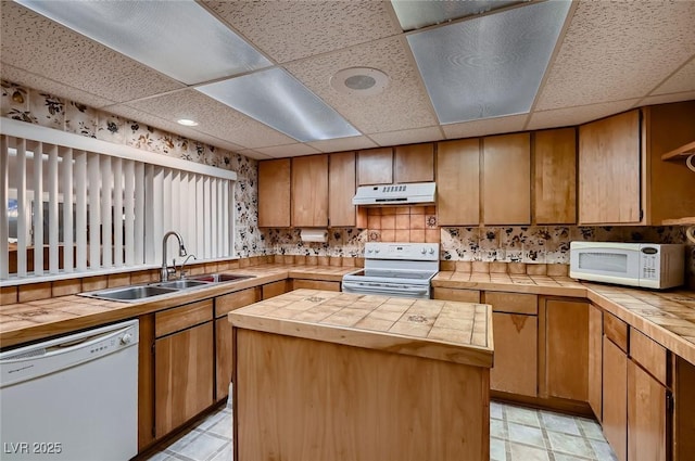 6213 Fairwood Ave, Las Vegas, NV 89107 - kitchen with white appliances, under cabinet range hood, a paneled ceiling, tile countertops, and a center island
