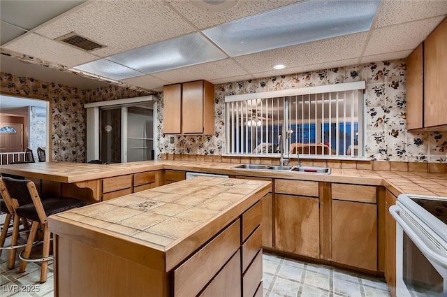 6213 Fairwood Ave, Las Vegas, NV 89107 - kitchen with wallpapered walls, a paneled ceiling, tile countertops, white range with electric cooktop, and a center island