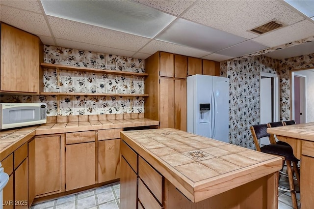 6213 Fairwood Ave, Las Vegas, NV 89107 - kitchen featuring white appliances, tile countertops, open shelves, a drop ceiling, and wallpapered walls