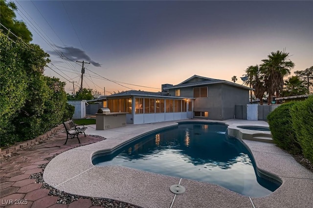 6213 Fairwood Ave, Las Vegas, NV 89107 - pool at dusk with a sunroom, a patio area, a fenced backyard, and a pool with connected hot tub