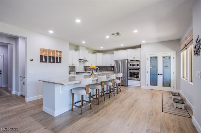 7445 Mezzanine View Ave, Las Vegas, NV 89178 - kitchen featuring stainless steel appliances, a kitchen breakfast bar, light wood-style floors, white cabinets, and recessed lighting
