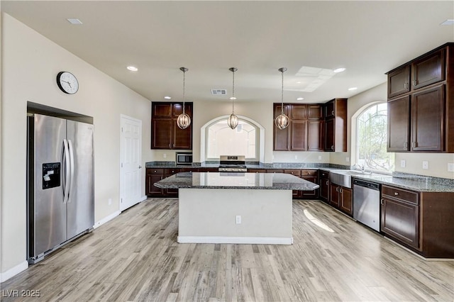 8565 Silver Coast St, Las Vegas, NV 89139 - kitchen with appliances with stainless steel finishes, dark stone counters, dark brown cabinets, a center island, and recessed lighting