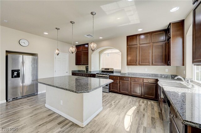 8565 Silver Coast St, Las Vegas, NV 89139 - kitchen featuring stainless steel appliances, arched walkways, light wood finished floors, dark stone countertops, and recessed lighting