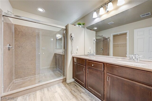 8565 Silver Coast St, Las Vegas, NV 89139 - bathroom featuring a shower stall, double vanity, a walk in closet, recessed lighting, and wood finished floors