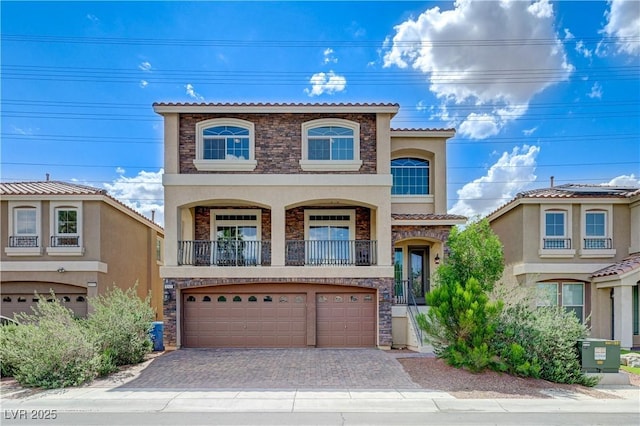 8565 Silver Coast St, Las Vegas, NV 89139 - view of front of home with stone siding, stucco siding, a garage, a balcony, and driveway