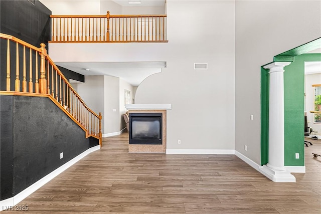 3405 Brook Song Ave, North Las Vegas, NV 89081 - unfurnished living room featuring a towering ceiling, wood finished floors, decorative columns, stairs, and a fireplace