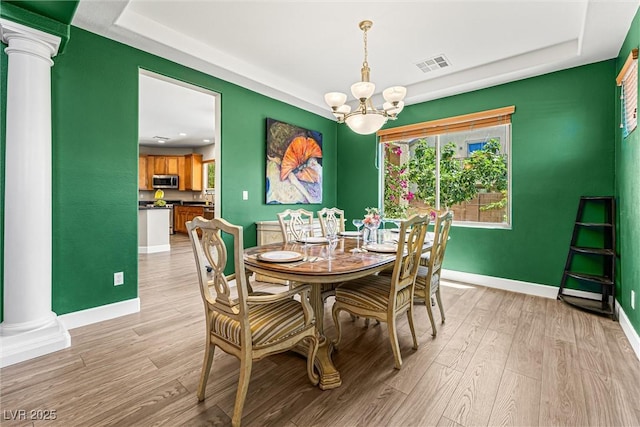 3405 Brook Song Ave, North Las Vegas, NV 89081 - dining area with ornate columns, a chandelier, a tray ceiling, and light wood finished floors