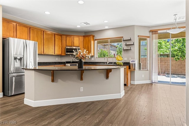 3405 Brook Song Ave, North Las Vegas, NV 89081 - kitchen with appliances with stainless steel finishes, dark wood-style flooring, a kitchen island, a breakfast bar area, and recessed lighting