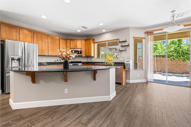 3405 Brook Song Ave, North Las Vegas, NV 89081 - kitchen with stainless steel appliances, dark wood finished floors, recessed lighting, a kitchen island, and a kitchen breakfast bar