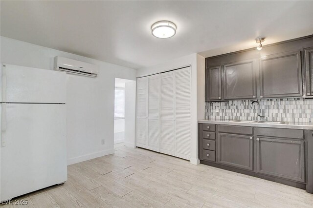 1708 Cedar Ave, Las Vegas, NV 89101 - kitchen featuring freestanding refrigerator, a wall mounted air conditioner, gray cabinets, light countertops, and tasteful backsplash