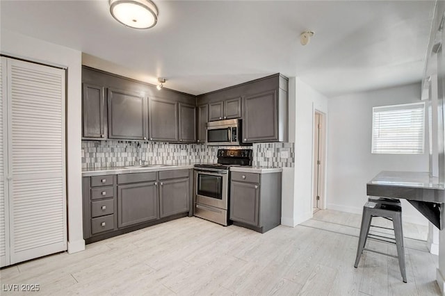 1708 Cedar Ave, Las Vegas, NV 89101 - kitchen with appliances with stainless steel finishes, light countertops, tasteful backsplash, and light wood-style flooring