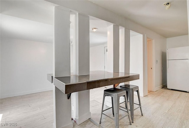 1708 Cedar Ave, Las Vegas, NV 89101 - kitchen with freestanding refrigerator, light wood-style flooring, and a kitchen bar