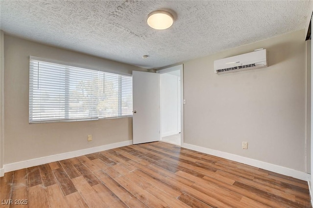 1708 Cedar Ave, Las Vegas, NV 89101 - unfurnished room with a wall mounted AC, wood finished floors, and a textured ceiling