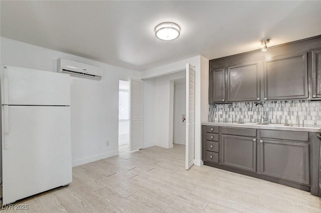 1708 Cedar Ave, Las Vegas, NV 89101 - kitchen with freestanding refrigerator, an AC wall unit, light countertops, tasteful backsplash, and light wood-style flooring
