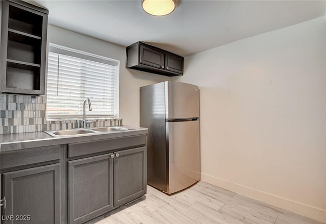 1708 Cedar Ave, Las Vegas, NV 89101 - kitchen with freestanding refrigerator, gray cabinets, light wood-style flooring, tasteful backsplash, and light countertops