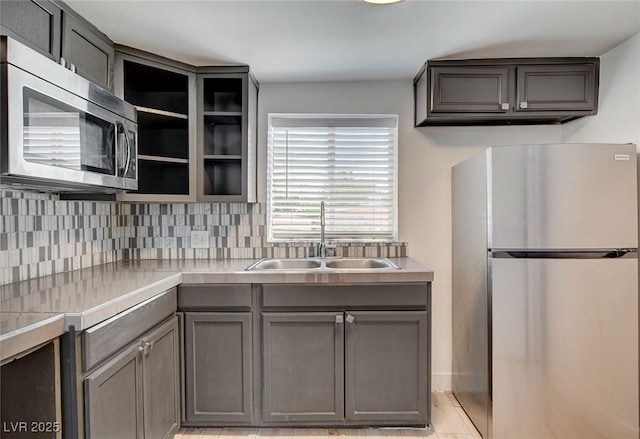 1708 Cedar Ave, Las Vegas, NV 89101 - kitchen with appliances with stainless steel finishes, gray cabinetry, light countertops, backsplash, and open shelves