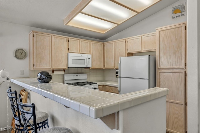 5139 Zapata Ln, North Las Vegas, NV 89031 - kitchen with white appliances, light brown cabinetry, tasteful backsplash, a peninsula, and a breakfast bar
