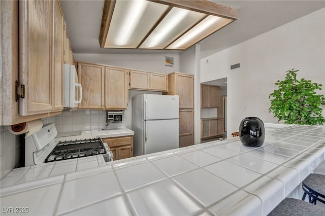 5139 Zapata Ln, North Las Vegas, NV 89031 - kitchen with white appliances, tile counters, light brown cabinets, tasteful backsplash, and a peninsula