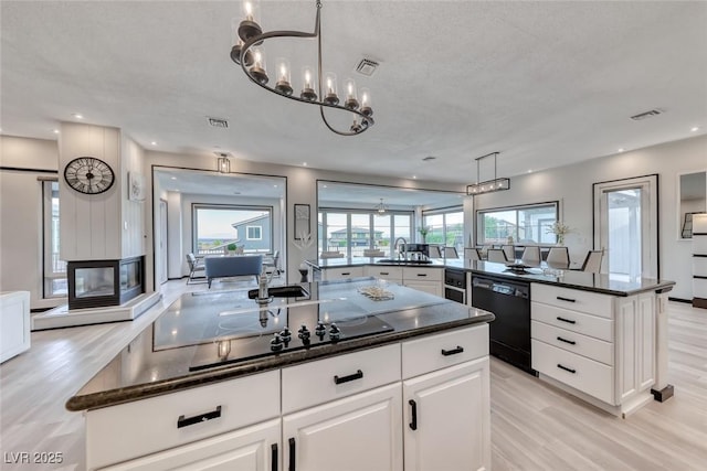 5438 Sierra Brook Ct, Las Vegas, NV 89149 - kitchen with black appliances, light wood-style flooring, a large island, white cabinets, and recessed lighting