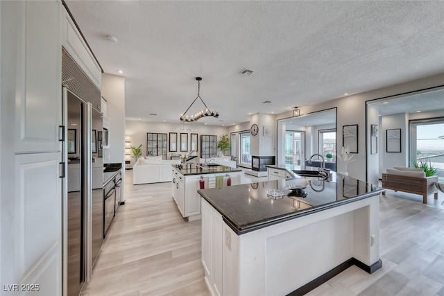 5438 Sierra Brook Ct, Las Vegas, NV 89149 - kitchen with a large island, open floor plan, light wood-style floors, stainless steel built in fridge, and white cabinets