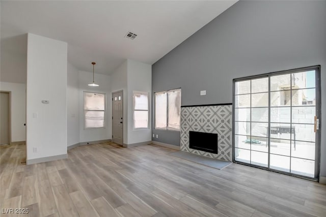 116 Lotus Blossom Ct, Las Vegas, NV 89145 - unfurnished living room with high vaulted ceiling, a tile fireplace, and light wood-style floors