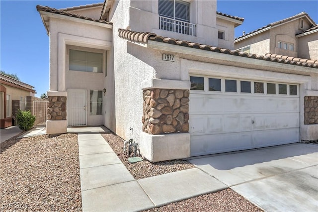 7977 Blue Brook Dr, Las Vegas, NV 89147 - mediterranean / spanish home with concrete driveway, a tiled roof, stone siding, stucco siding, and an attached garage
