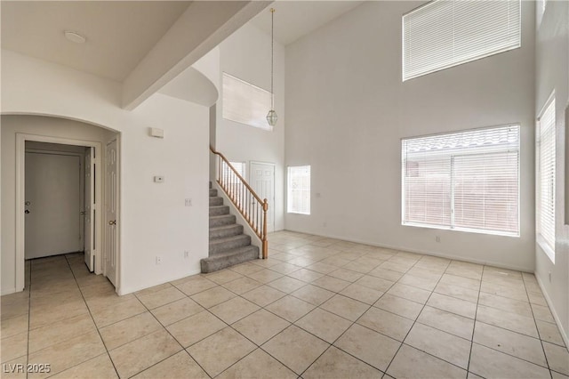 7977 Blue Brook Dr, Las Vegas, NV 89147 - spare room with a towering ceiling, light tile patterned floors, stairs, and plenty of natural light