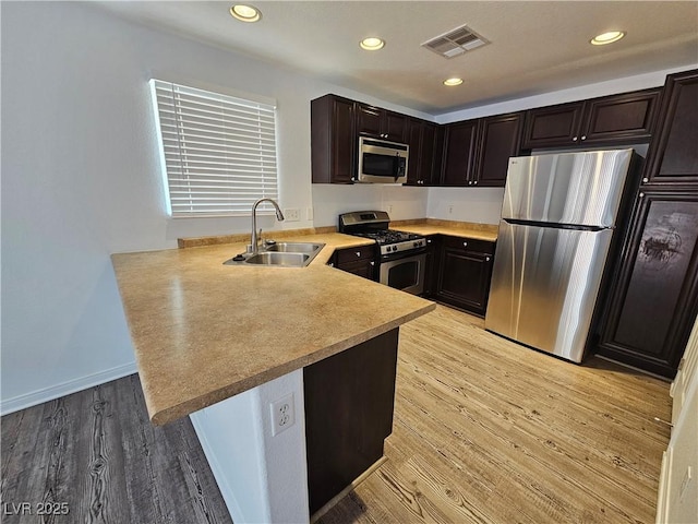 6824 Briarwood Bend Ave, Las Vegas, NV 89130 - kitchen with stainless steel appliances, a peninsula, light wood-type flooring, dark brown cabinetry, and light countertops