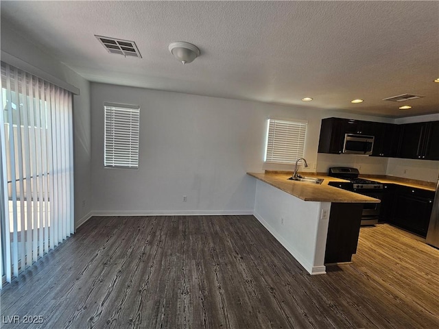 6824 Briarwood Bend Ave, Las Vegas, NV 89130 - kitchen with stainless steel appliances, dark cabinetry, wood finished floors, a textured ceiling, and recessed lighting