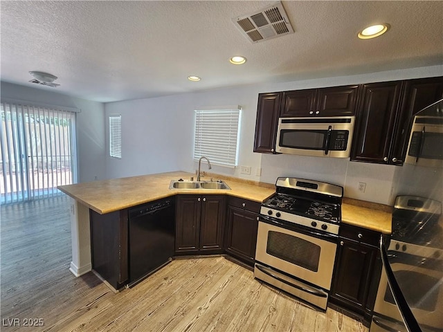 6824 Briarwood Bend Ave, Las Vegas, NV 89130 - kitchen featuring appliances with stainless steel finishes, light countertops, light wood-style floors, a peninsula, and a textured ceiling