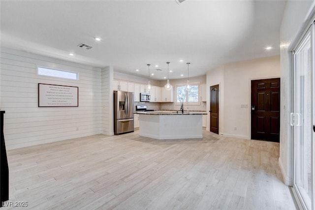 10556 Sariah Skye Ave, Las Vegas, NV 89166 - kitchen with stainless steel appliances, white cabinetry, light wood-type flooring, a center island, and open floor plan
